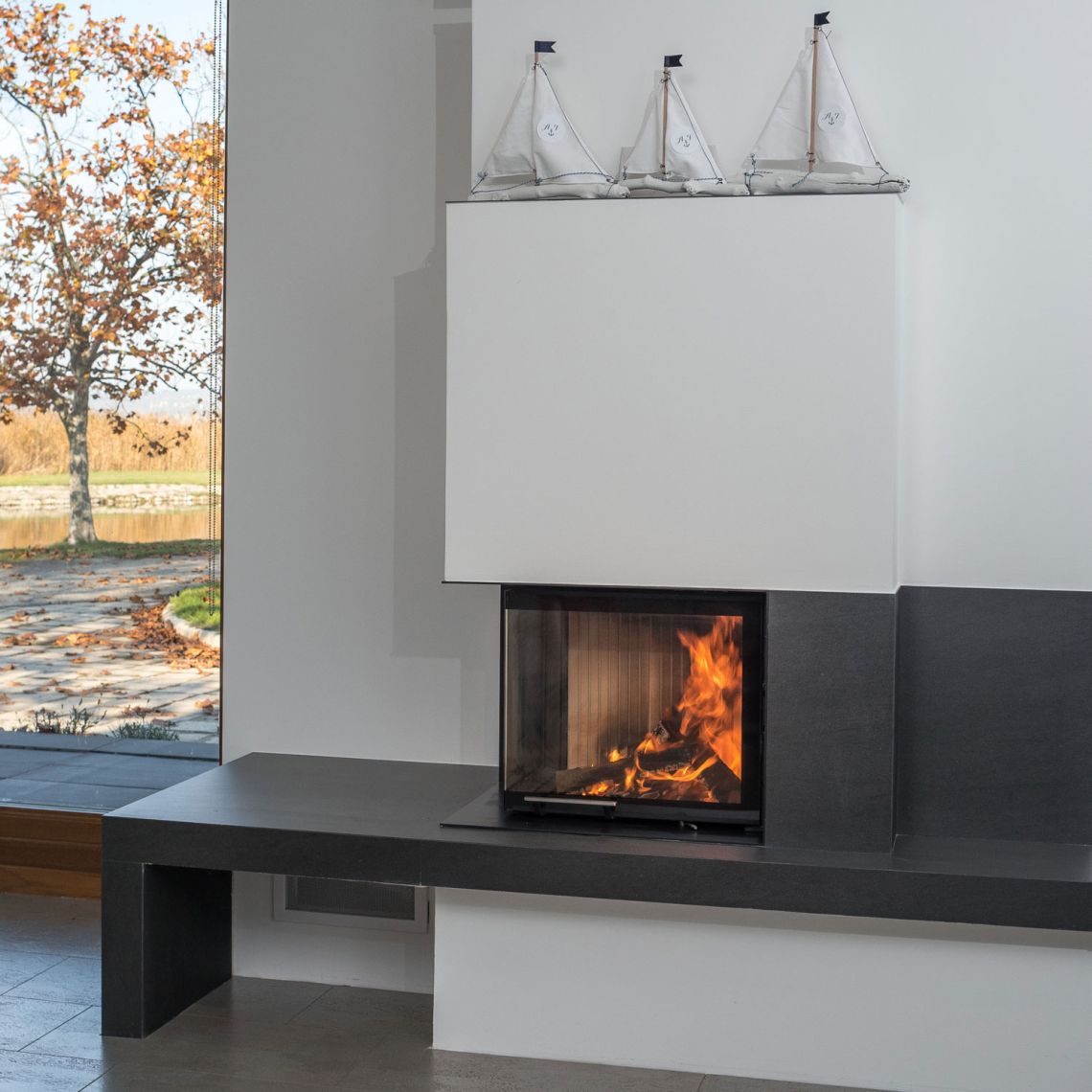 Eck-Cheminée mit 2-seitiger, hochschiebbarer Glasscheibe und Cheminéebank.