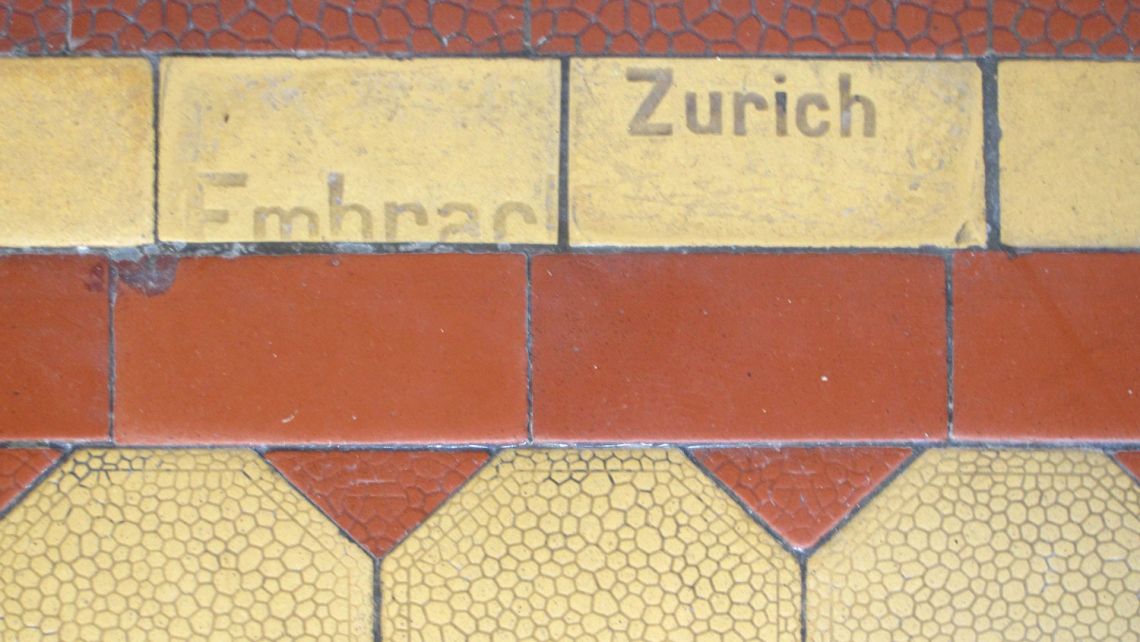 Ausschnitt des historischen Klinkerbodens im Schulhaus Gubel auf dem Embrach und Zurich als Vertiefung zu sehen ist.