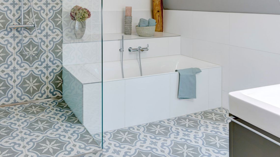 Retroplättli in gedeckten blau- und grüntönen setzen Akzente im Bad.